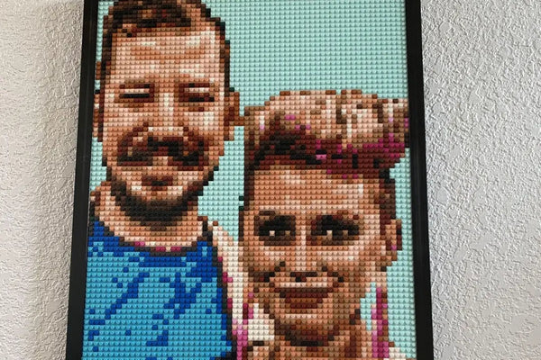 A finished brick mosaic of a smiling couple, framed and hanging on a wall at home